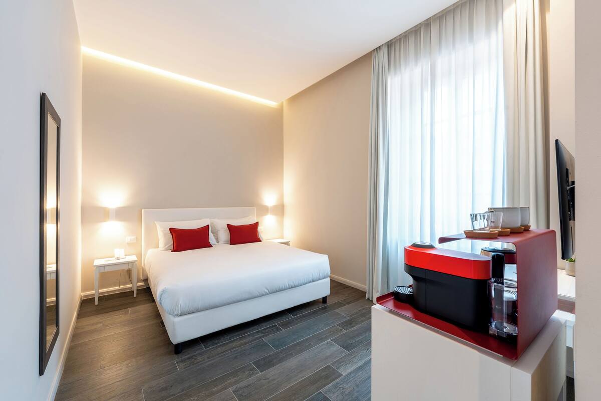 Ein Hotelzimmer mit Bett, Nachttischen, einer Kaffeemaschine und einem Fernseher.
