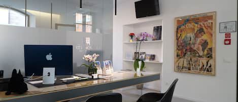 Un mostrador de recepción con una iMac de Apple, una silla negra y un cartel en la pared.