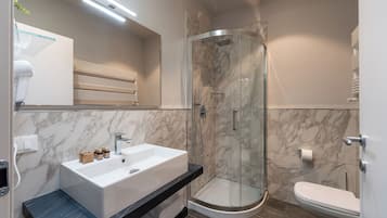 Une salle de bain moderne avec une douche à parois de verre, un lavabo blanc et des toilettes.