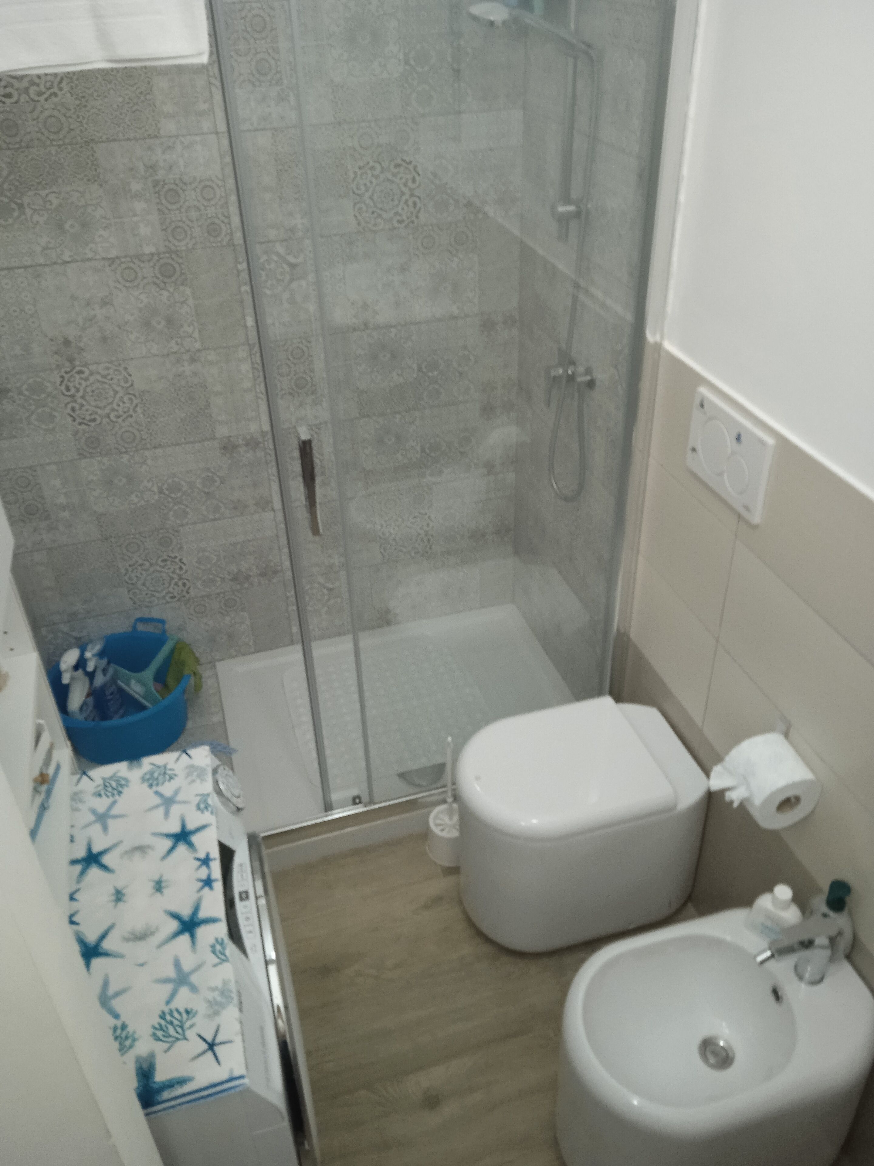 Ein Badezimmer mit Dusche, Toilette, Waschbecken und einem blauen Korb.