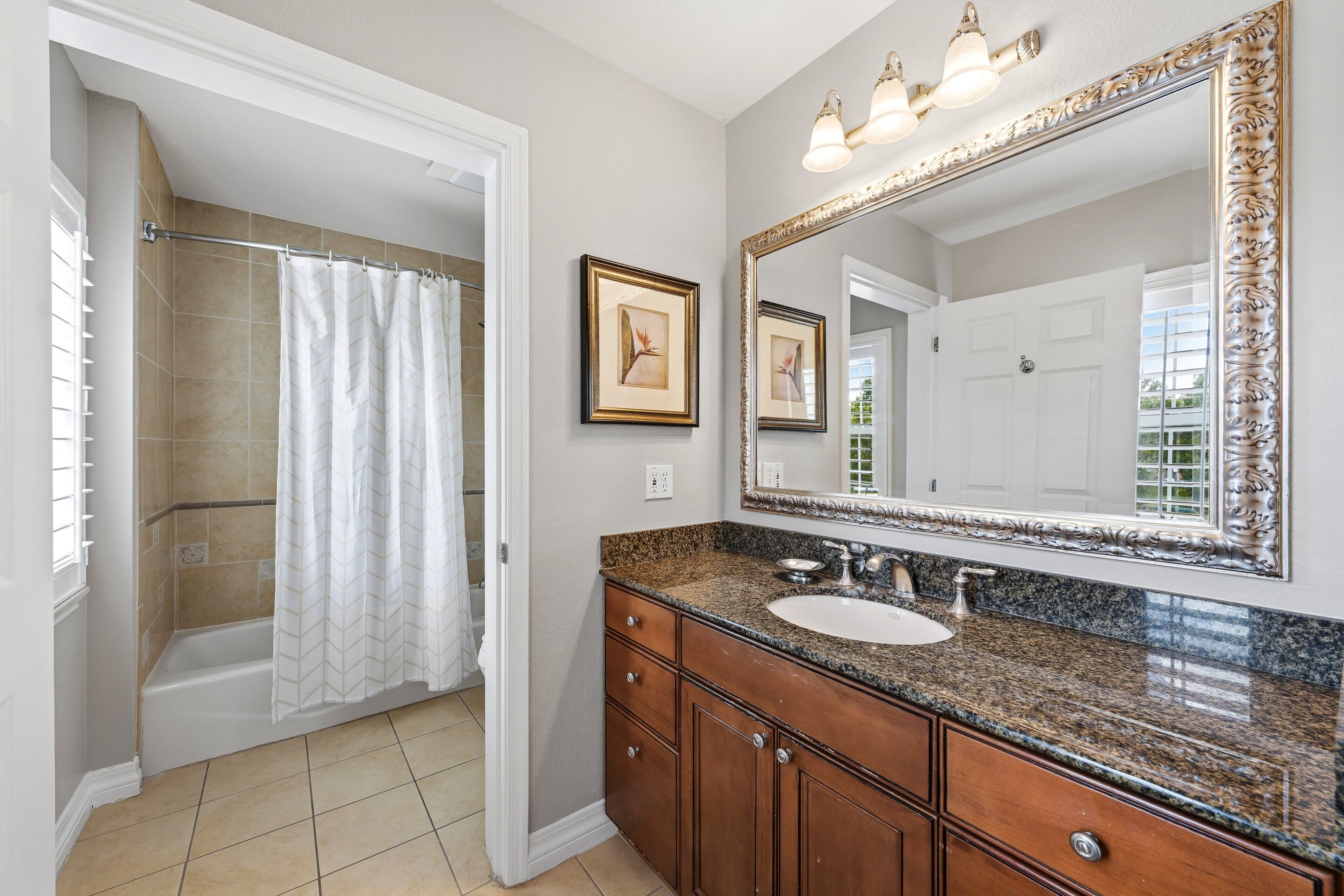 Une salle de bain avec une douche, un lavabo, un meuble-lavabo et un grand miroir.