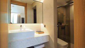 A modern bathroom with a white marble sink, a large mirror, and a glass-enclosed shower.