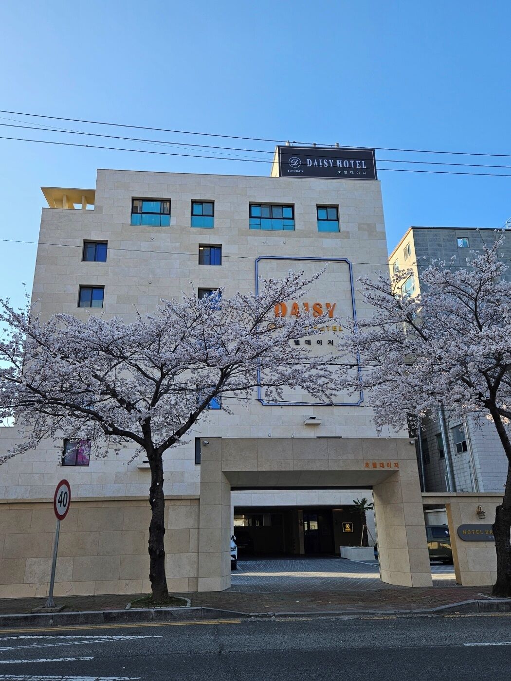 Un bâtiment sur lequel on peut lire l’inscription « HÔTEL DAISY » et où est affiché un panneau indiquant la vitesse maximale autorisée, soit 40.