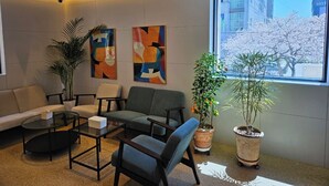 A modern waiting area with a sofa, chairs, a coffee table, and potted plants. - Daisy Hotel (Tongyeong)