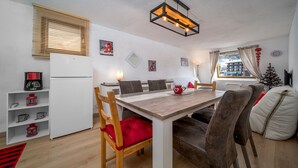 Een gezellig eetgedeelte met een houten tafel, vier stoelen en een moderne hanglamp.