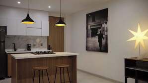 A modern kitchen with a central island, two bar stools, pendant lighting, a coffee machine, and a star-shaped lamp. - Villa Milá A3- Luxury sunset view - Close to everything (Salento)