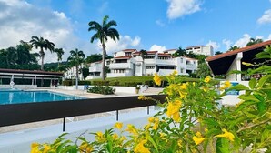 A pool area with a clear sky, palm trees, and a building with multiple balconies. - Blue Villa Retreat (Río Grande)