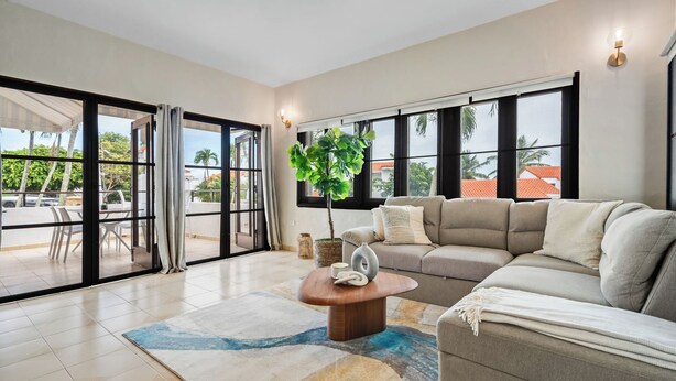A spacious living room with a large window, a sofa, a coffee table, and a potted plant. - Blue Villa Retreat (Río Grande)