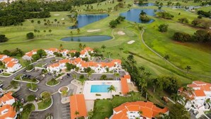 A golf course with multiple ponds, a swimming pool, and residential buildings with red roofs. - Blue Villa Retreat (Río Grande)