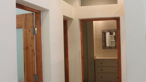 Ein schmaler Flur mit Holztüren und einem Badezimmer mit Spiegel und Schrank.