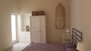 Ein Schlafzimmer mit Bett, Kleiderschrank, Nachttisch und Buddha-Statue.