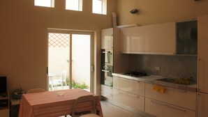 Eine Küche mit Essbereich, einem Fernseher und einer Tür, die auf eine Terrasse im Freien führt.