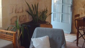 A room with a stone wall, a painting of a woman, a blue cabinet, and a potted plant. - Farmhouse With Pool and Valley Views (Munxar)