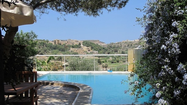 A swimming pool with a view of a hillside town. - Farmhouse With Pool and Valley Views (Munxar)