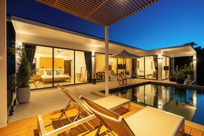 Una casa moderna con piscina, mobiliario exterior y un interior bien iluminado.