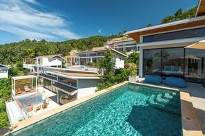 Una casa moderna con piscina, varios niveles y vistas al bosque circundante.