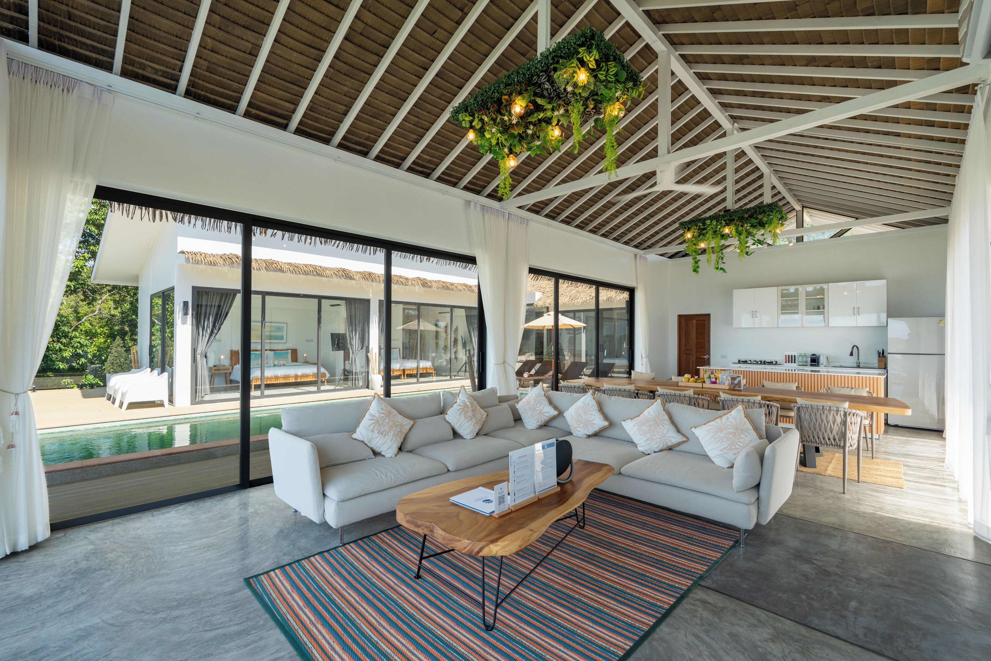 A spacious living area with a large sofa, a coffee table, and a kitchen in the background.