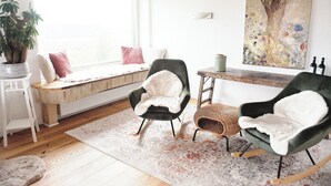 A cozy living room with a bench by the window, two armchairs, a wooden table, and a large painting on the wall. - Modern, spacious top-floor apartment with panoramic views of the Elbe (Hollern-Twielenfleth)