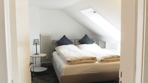 A bedroom with a bed, a radiator, a lamp, and a skylight. - Modern, spacious top-floor apartment with panoramic views of the Elbe (Hollern-Twielenfleth)