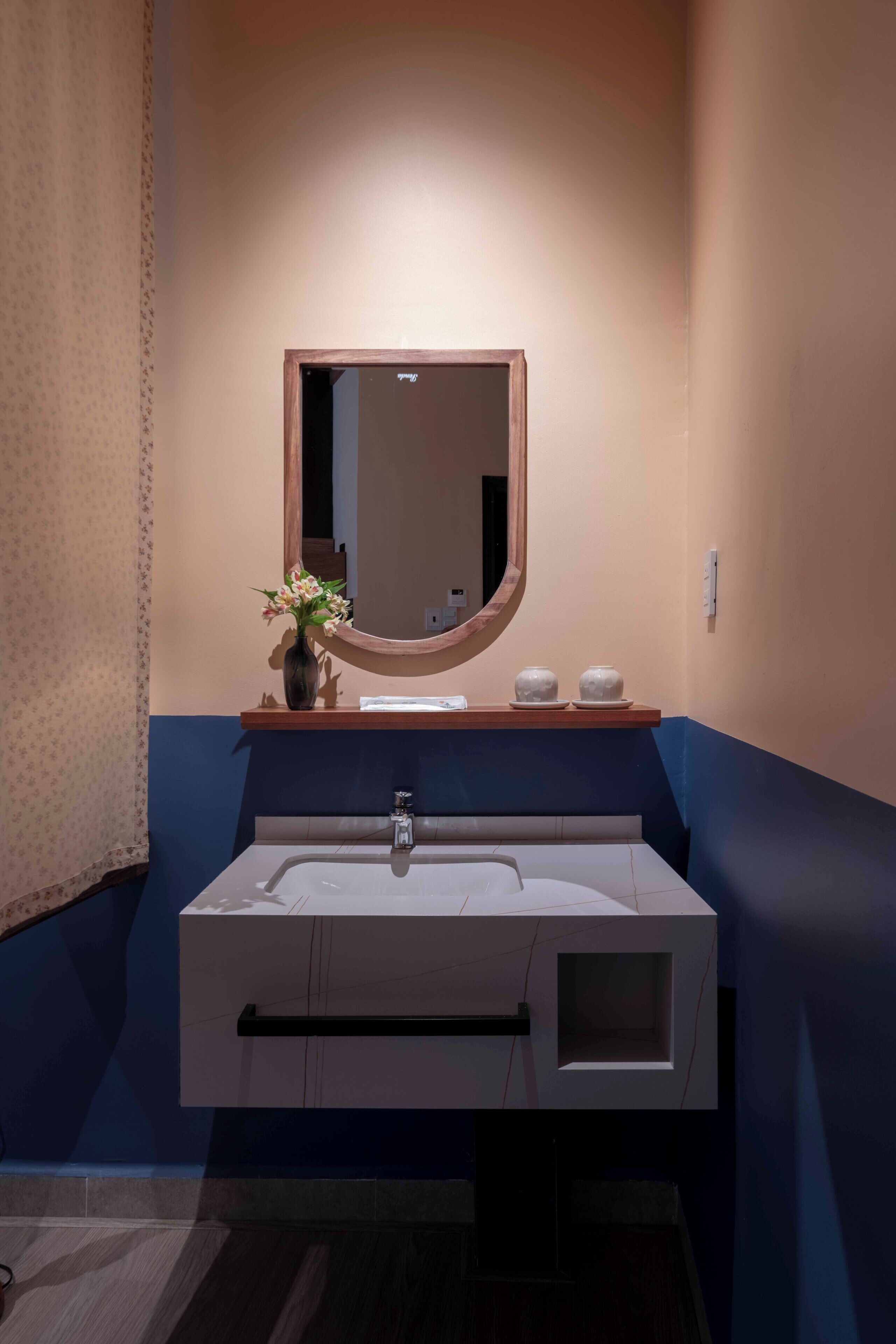 A modern bathroom with a large sink, a mirror, and a vase of flowers on the counter.