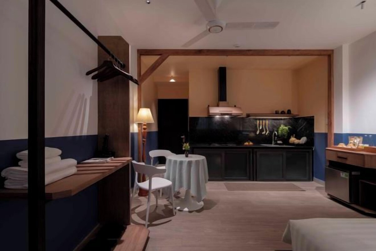 Una habitación de hotel compacta con kitchenette, un pequeño comedor y una cama.
