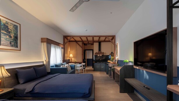 Een hotelkamer met twee bedden, een televisie, een bureau en een kitchenette.