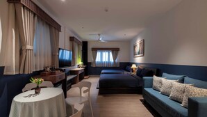 Een hotelkamer met een bed, een bank, een bureau met een computer, een stoel en een tafeltje met een vaas.