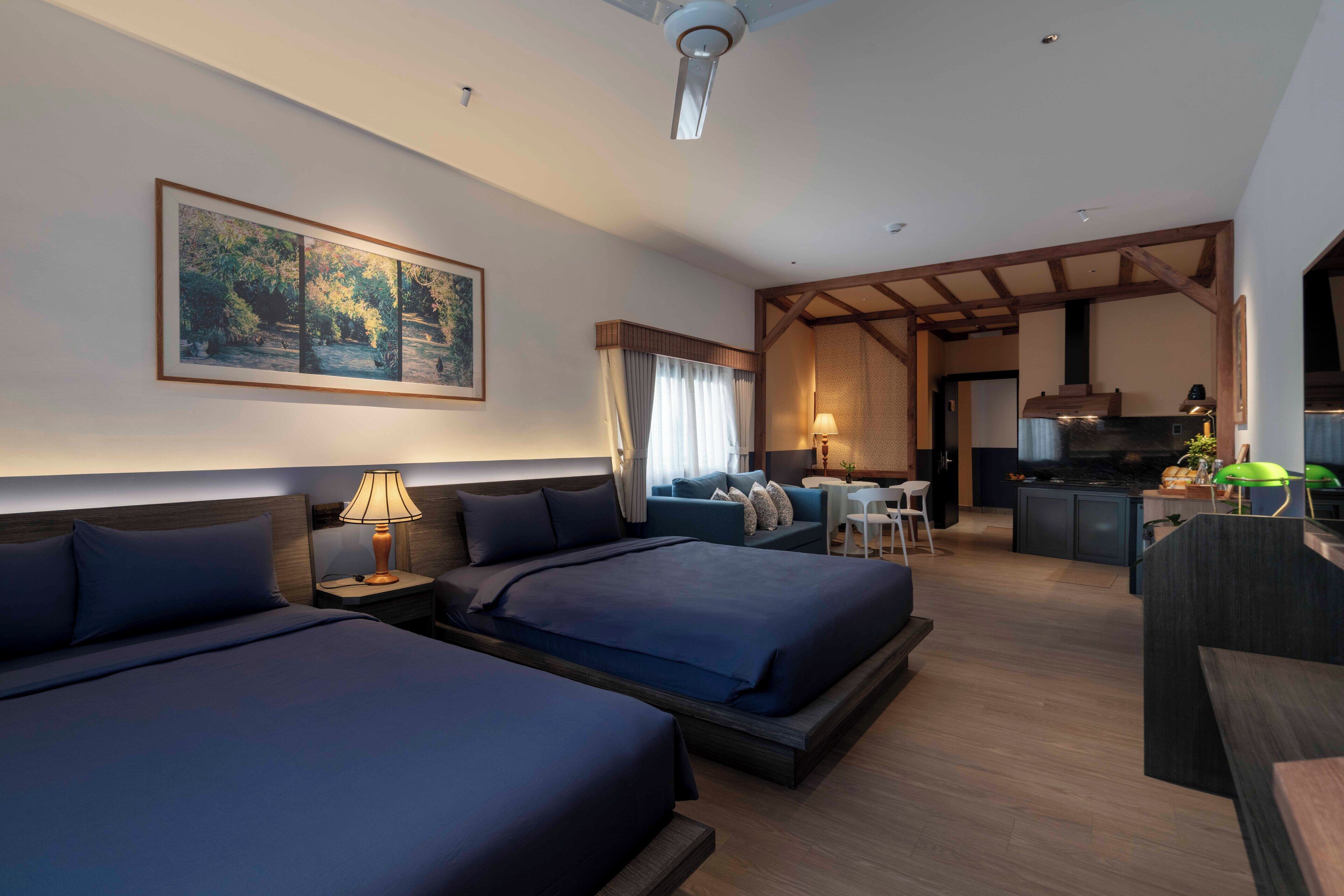 Une chambre d’hôtel avec deux lits, un bureau, une kitchenette et un coin repas.