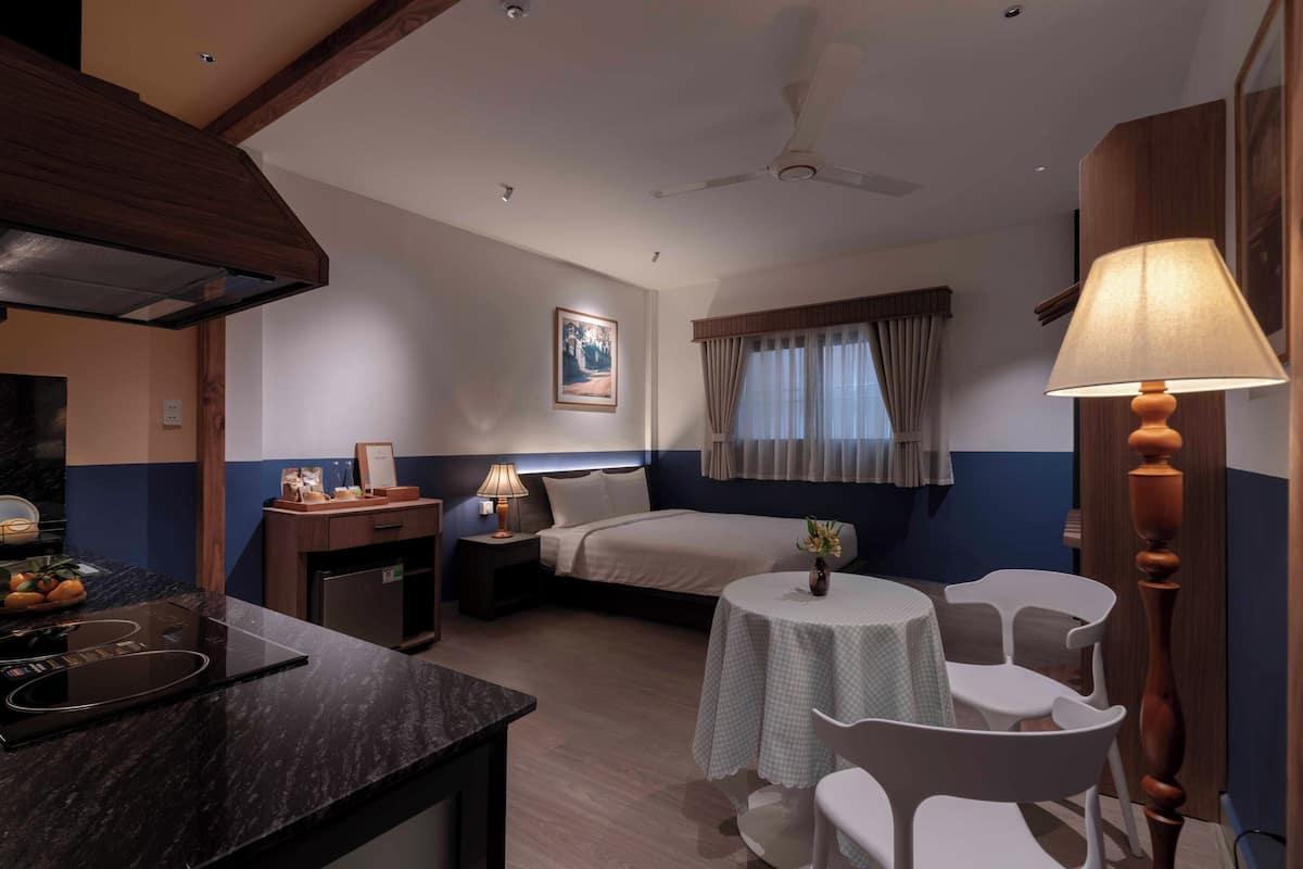 Une chambre d’hôtel comprenant un lit, une table de chevet, une lampe et une petite table ronde avec des chaises.
