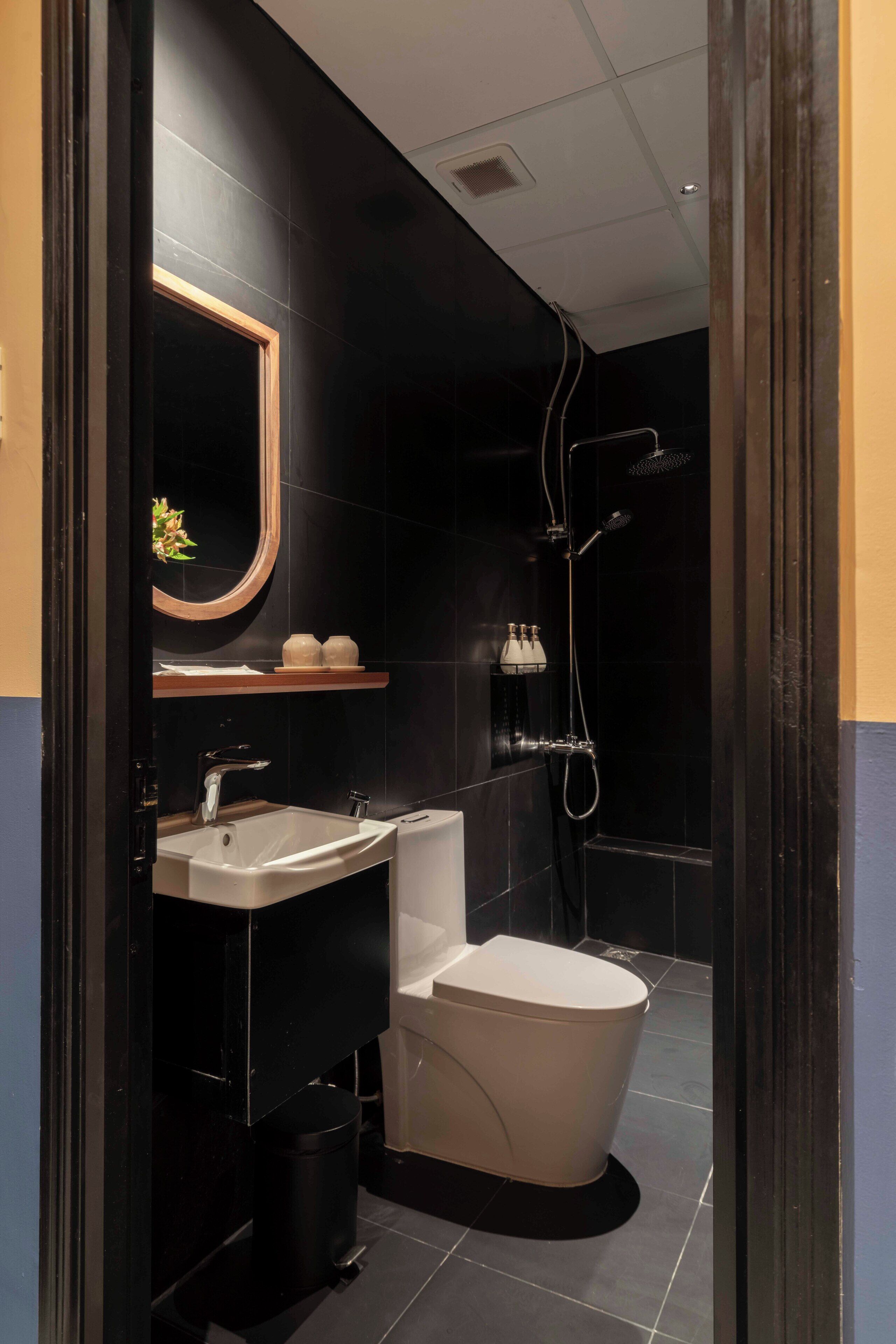 Une salle de bain moderne aux couleurs noir et blanc, comprenant un lavabo, des toilettes et une douche.