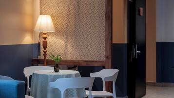 A room with a round table, white chairs, a lamp, and a patterned wall.