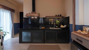 Een moderne keuken met donkere kastjes, een zwart marmeren spatwand en een inbouwfornuis.