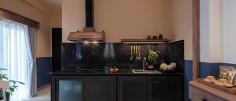A modern kitchen with dark cabinetry, a black marble backsplash, and a built-in stove.