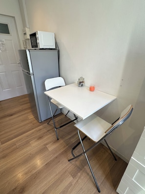 A compact kitchen with a microwave, a refrigerator, a small table, and a chair. - * Le 10 * Charming Studio (Mulhouse)