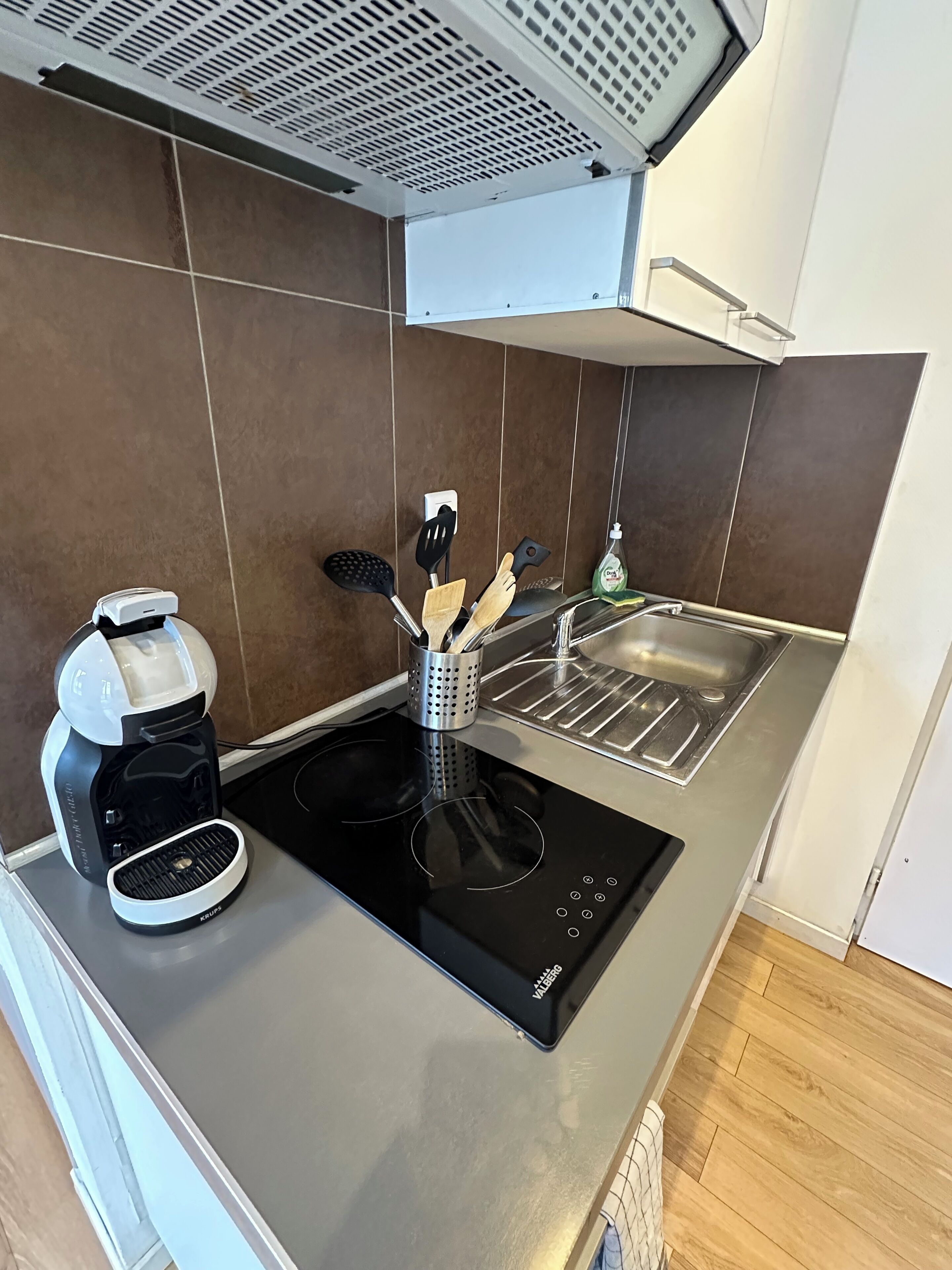 A modern kitchen with a built-in induction cooktop, a coffee maker, and a stainless steel sink.