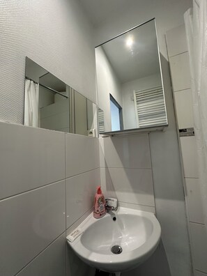 A bathroom with a white sink, a mirror, and a shower curtain.