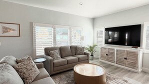 Una sala de estar moderna con sofá, una mesa de centro, televisor y un mueble aparador.