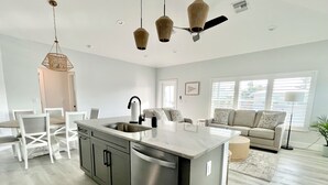 Una cocina moderna con una isla central, electrodomésticos de acero inoxidable e iluminación colgante.