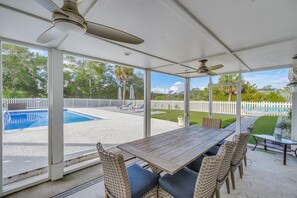 Um alpendre coberto com piscina, mobiliário de exterior e vista para o quintal.