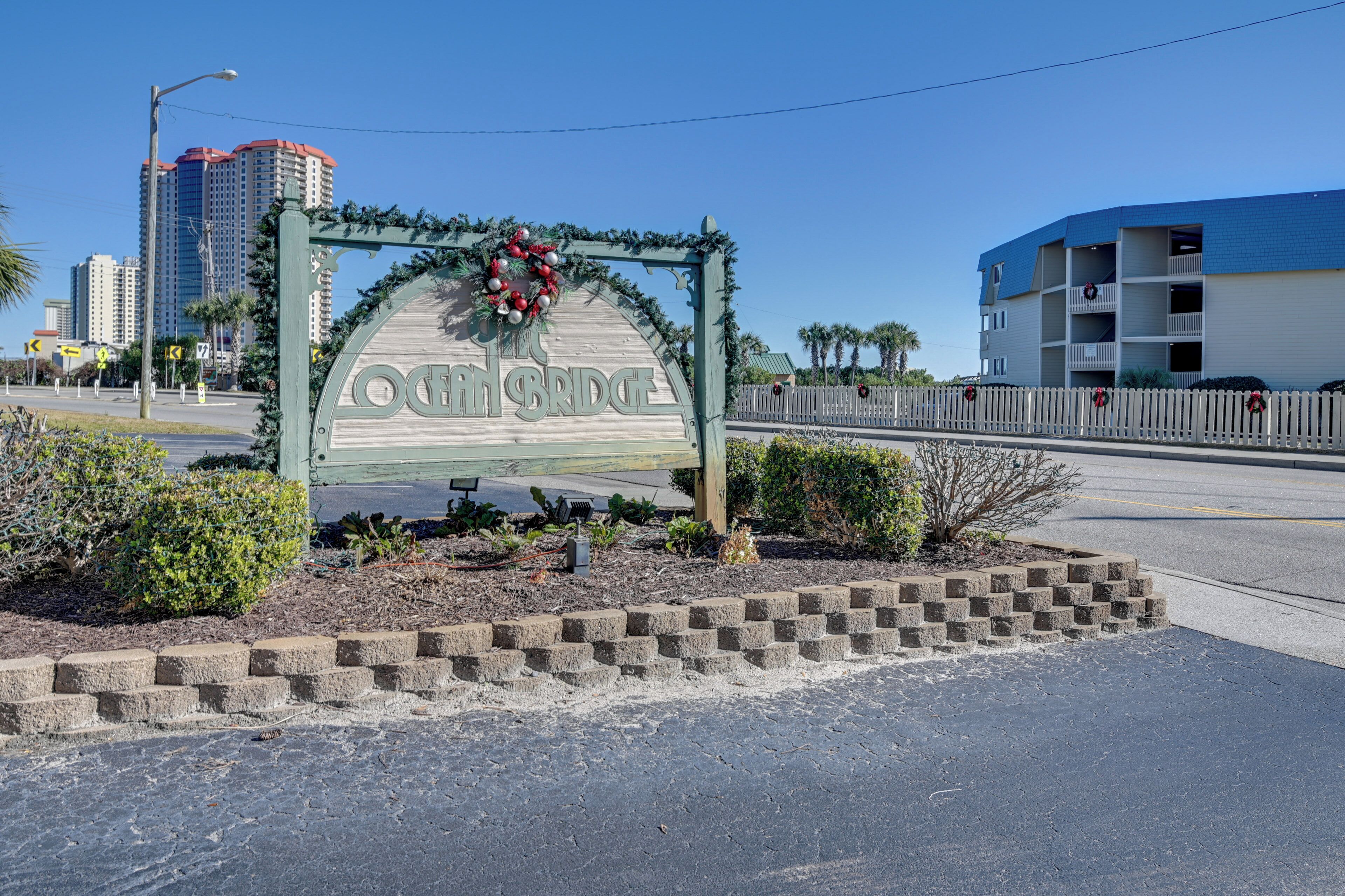 A sign with the name 'Ocean Bridge' surrounded by greenery and a decorative wreath.