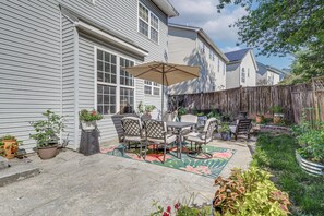 A patio with a table and chairs, a large umbrella, and potted plants.
