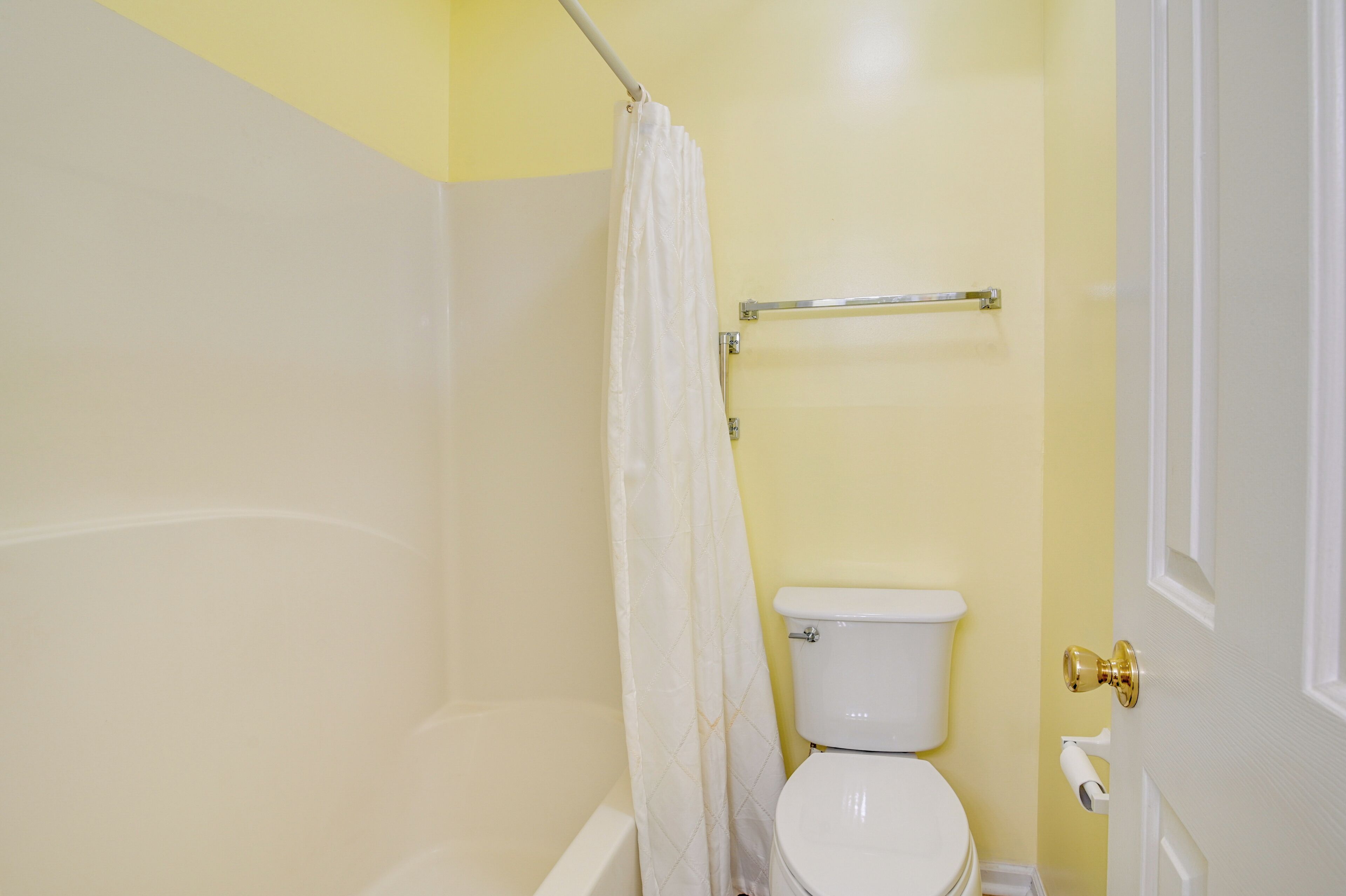 A bathroom with a white toilet, a shower curtain, and a towel rack.