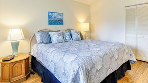 Een slaapkamer met een bed, twee bedlampen, een nachtkastje, een schilderij aan de muur en een kledingkast.