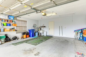 A garage with a concrete floor, shelves with various items, a workbench, and a door. - < 10 Mi to Dtwn Venice & Beach: Lake-view Home! (Venice)