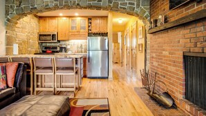 Une cuisine dotée d’une arche en pierre, de meubles en bois, d’appareils électroménagers en acier inoxydable et d’une cheminée.