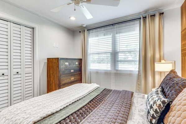 A bedroom with a bed, a dresser, a ceiling fan, and a window with curtains. - Fenced Yard: Lakeland Home Adjacent to Golf Course (Lakeland)