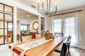A dining room with a long wooden table, two large vases, and a chandelier. - Fenced Yard: Lakeland Home Adjacent to Golf Course (Lakeland)