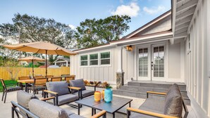 An outdoor patio with seating, a table, and umbrellas.