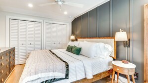 A bedroom with a bed, a dresser, a nightstand, a lamp, and a ceiling fan.