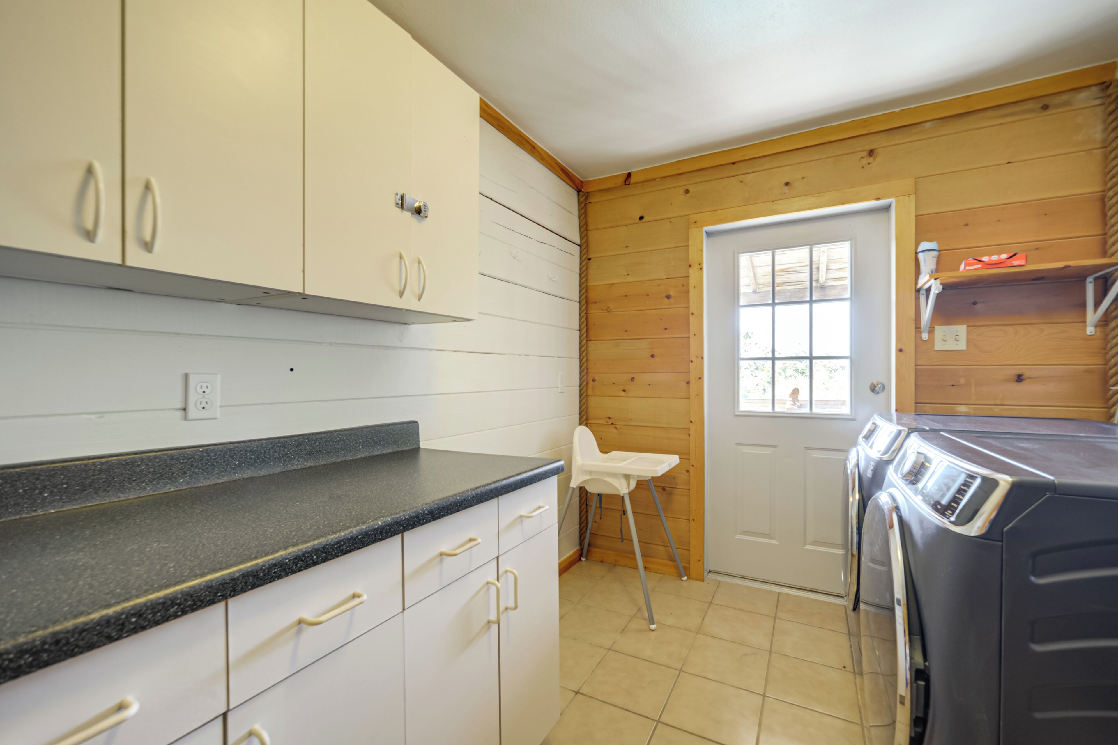 A kitchen with white cabinets, a black countertop, and a washing machine.
